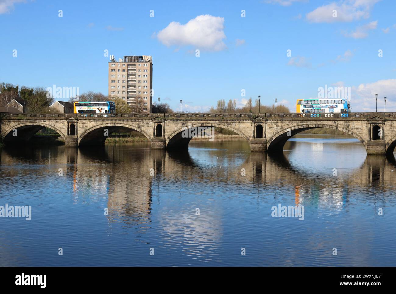 Stagecoach double deck buses crossing historic Skerton Bridge over River Lune in Lancaster, Lancashire, England at high tide on 30th March 2024. Stock Photo