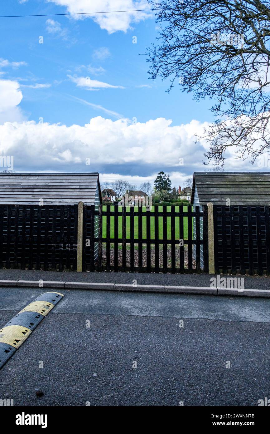 Leatherhead Surrey, UK, April 01 2024, Two Black Painted Wooden Sheds With Metal Fence And Tree In School Playing Fields With No People Stock Photo