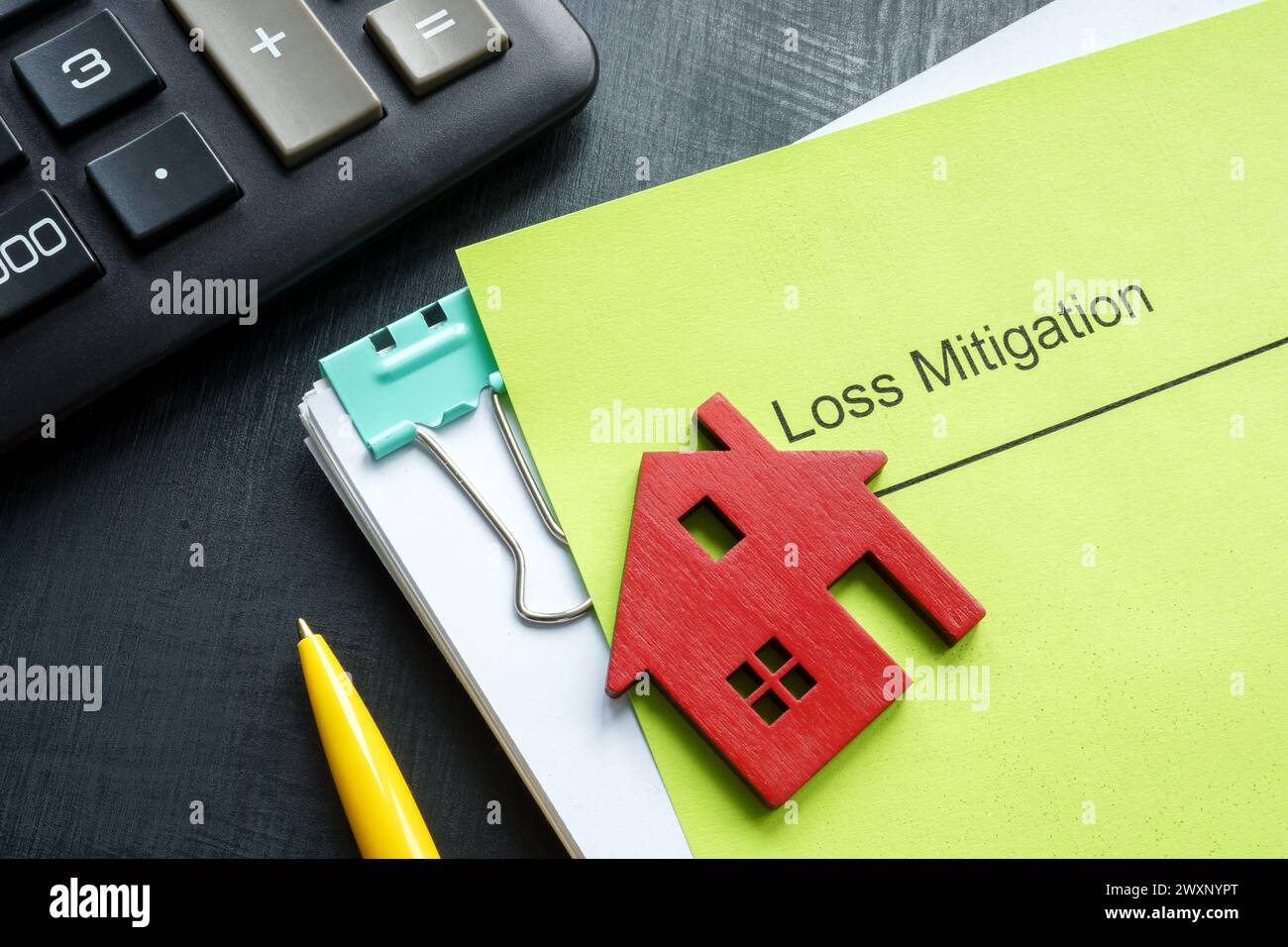 A stack of documents about loss mitigation with a figurine of a house ...