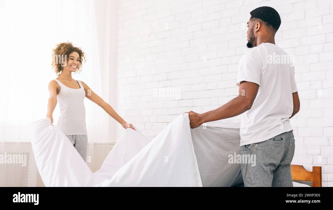Couple making the bed together happily at home Stock Photo