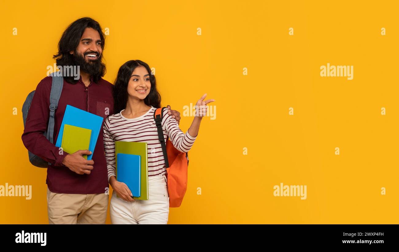 Two students holding books on yellow background Stock Photo - Alamy