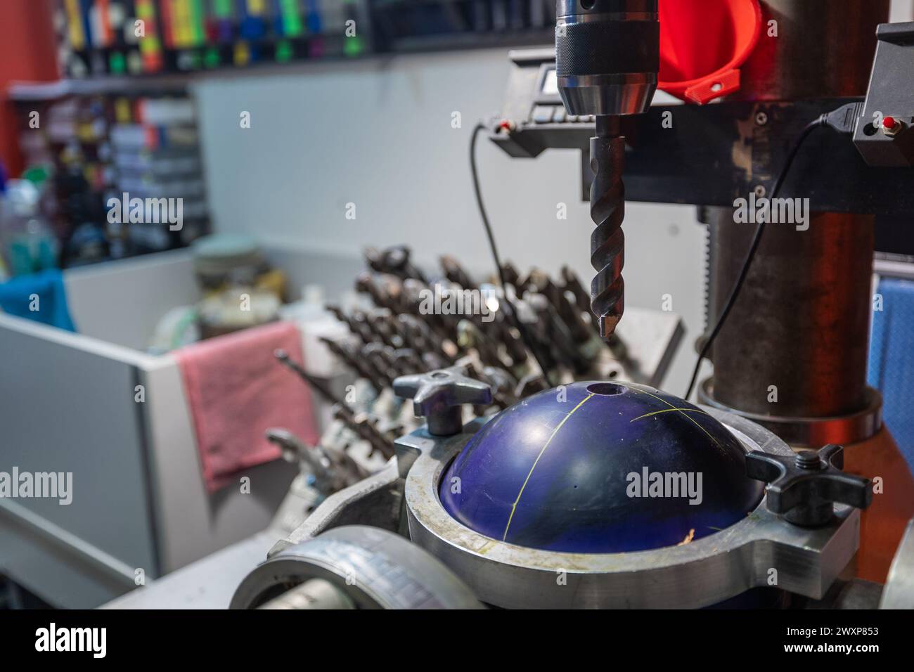 Drilling holes with a drill bit into bowling ball. Preparing bowling ball for a customer, custom holes with special size and diameter into a ball. Stock Photo