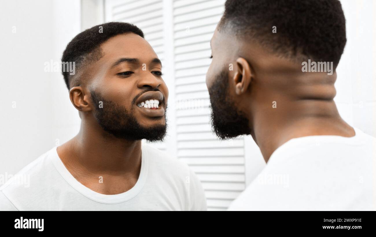 Man brushing teeth looking at bathroom mirror Stock Photo