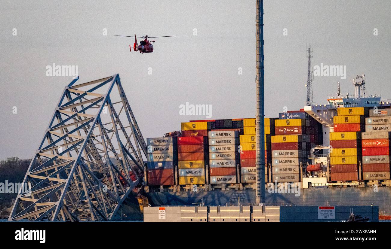 Baltimore, USA. 26th Mar, 2024. A Coast Guard helicopter flies over the ...