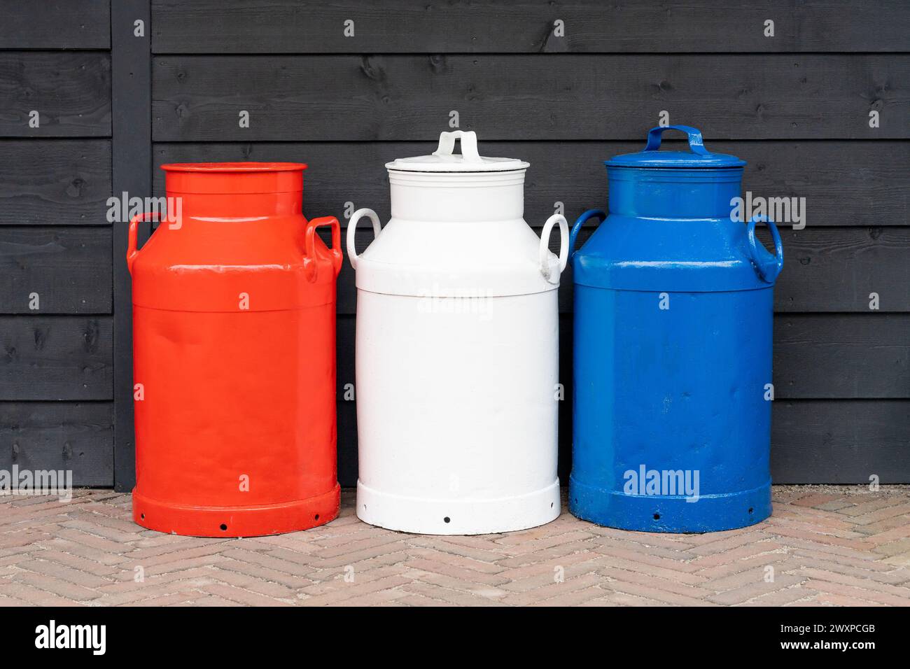 Vintage milk cans in the colors of the national flag of the Netherlands, dutch milk industry and farming equipment Stock Photo