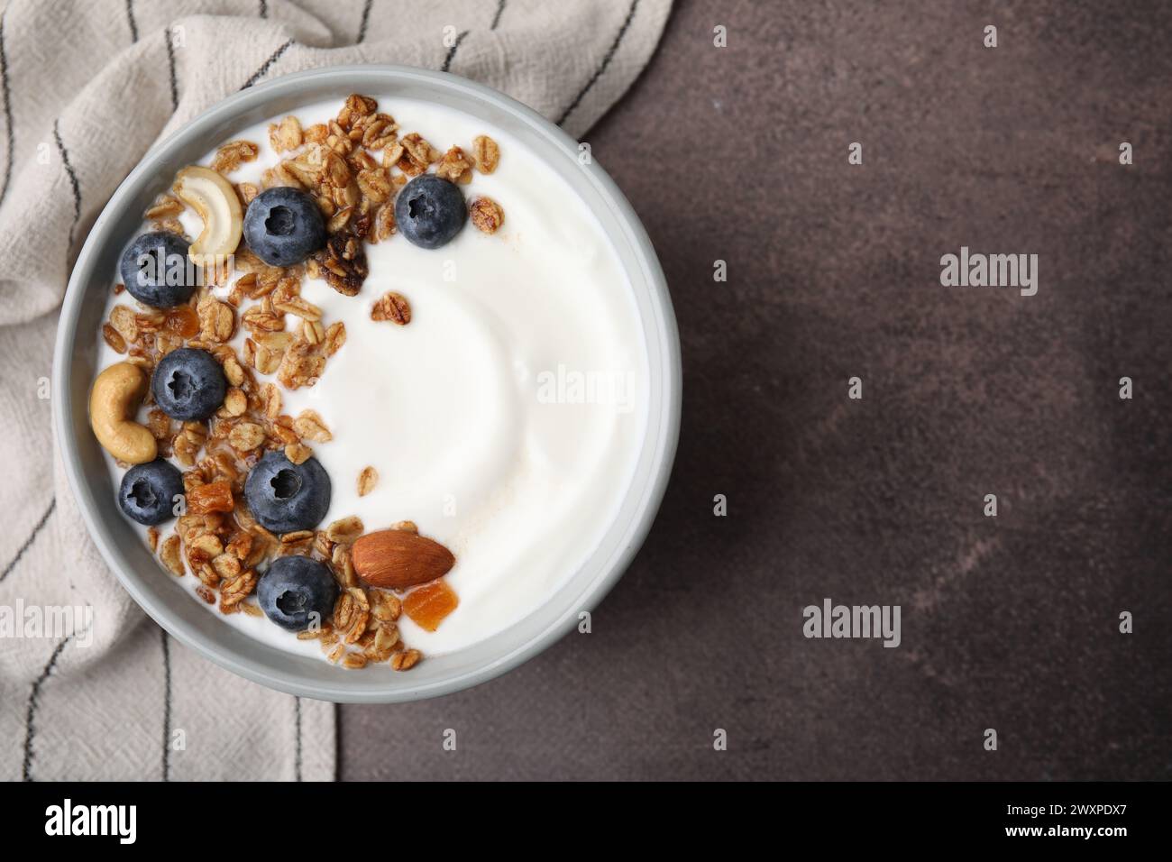 Bowl with yogurt, blueberries and granola on grey table, top view. Space for text Stock Photo