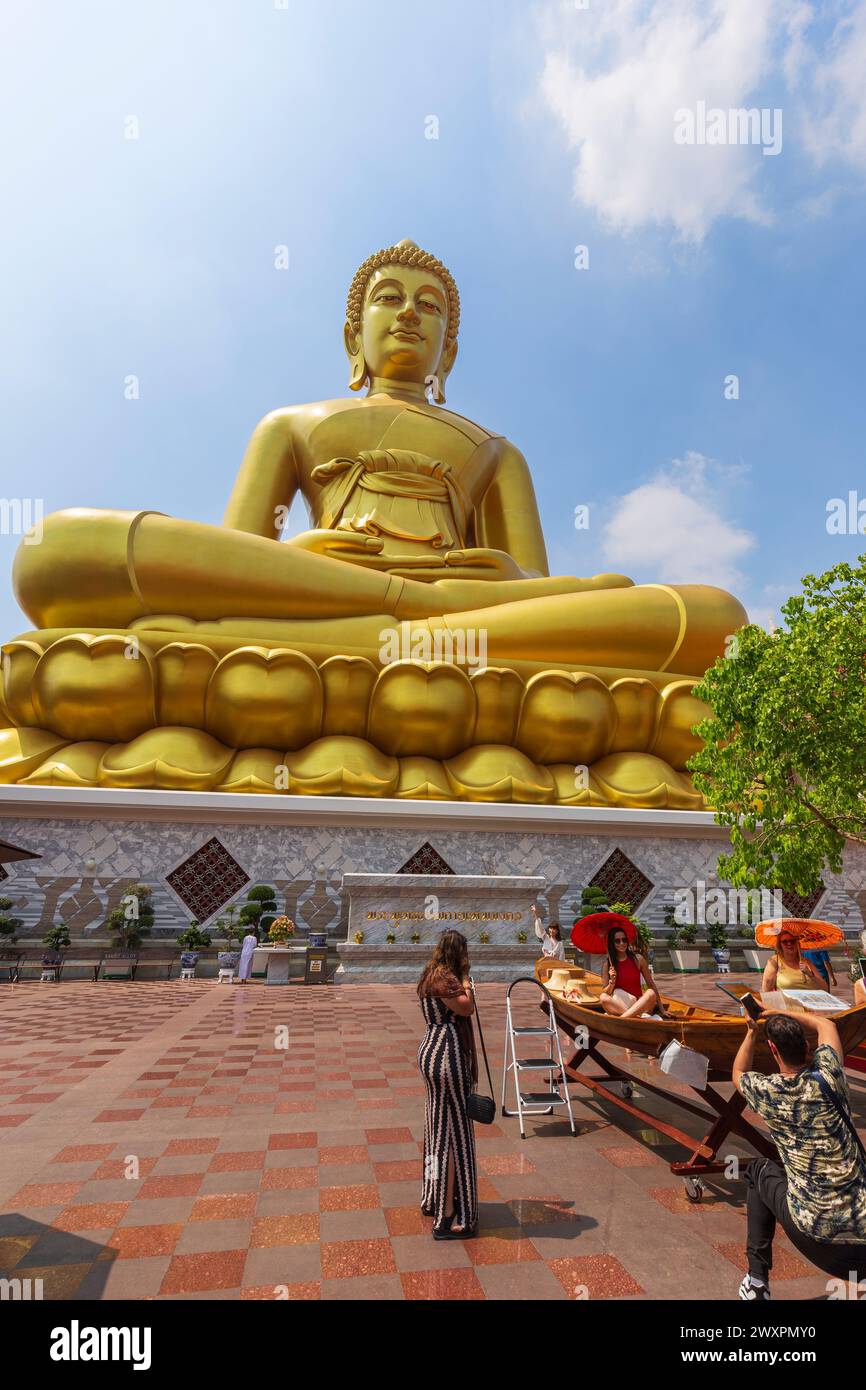 Tourists taking photos in front of the big & golden Buddha statue at the Wat Paknam (Pak Nam) Phasi Charoen Temple in Bangkok, Thailand on a sunny day Stock Photo