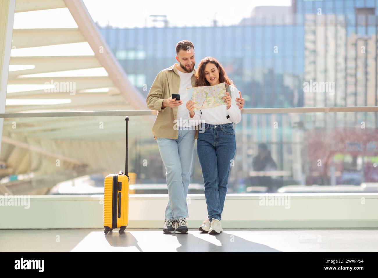 Loving couple holding map and using phone at airport Stock Photo
