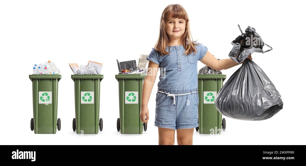 Little girl holding a plastic bin bag in front of trash cans with recycling materials isolated on white background Stock Photo