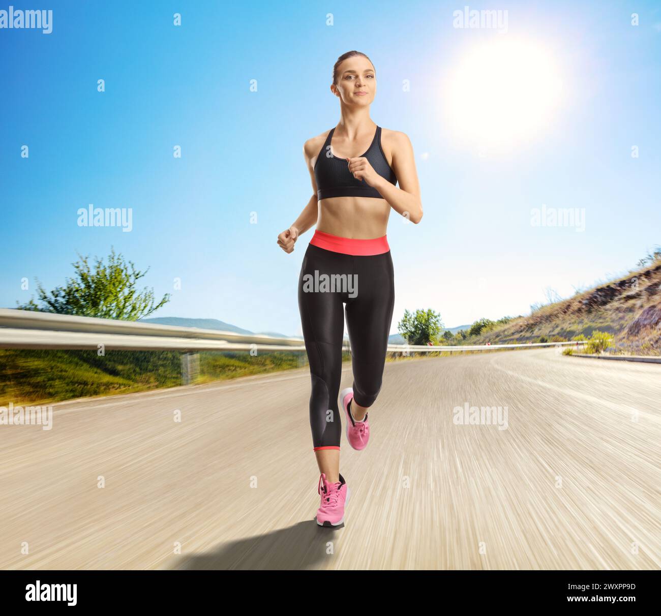 Young fit woman running on an open road on a sunny day Stock Photo