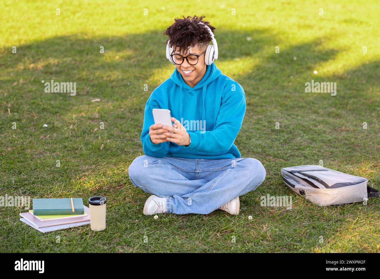 Student sitting outside using smartphone Stock Photo