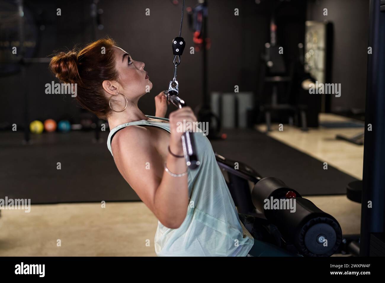 Woman fully engaged in a lat pulldown exercise at the gym, highlighting ...