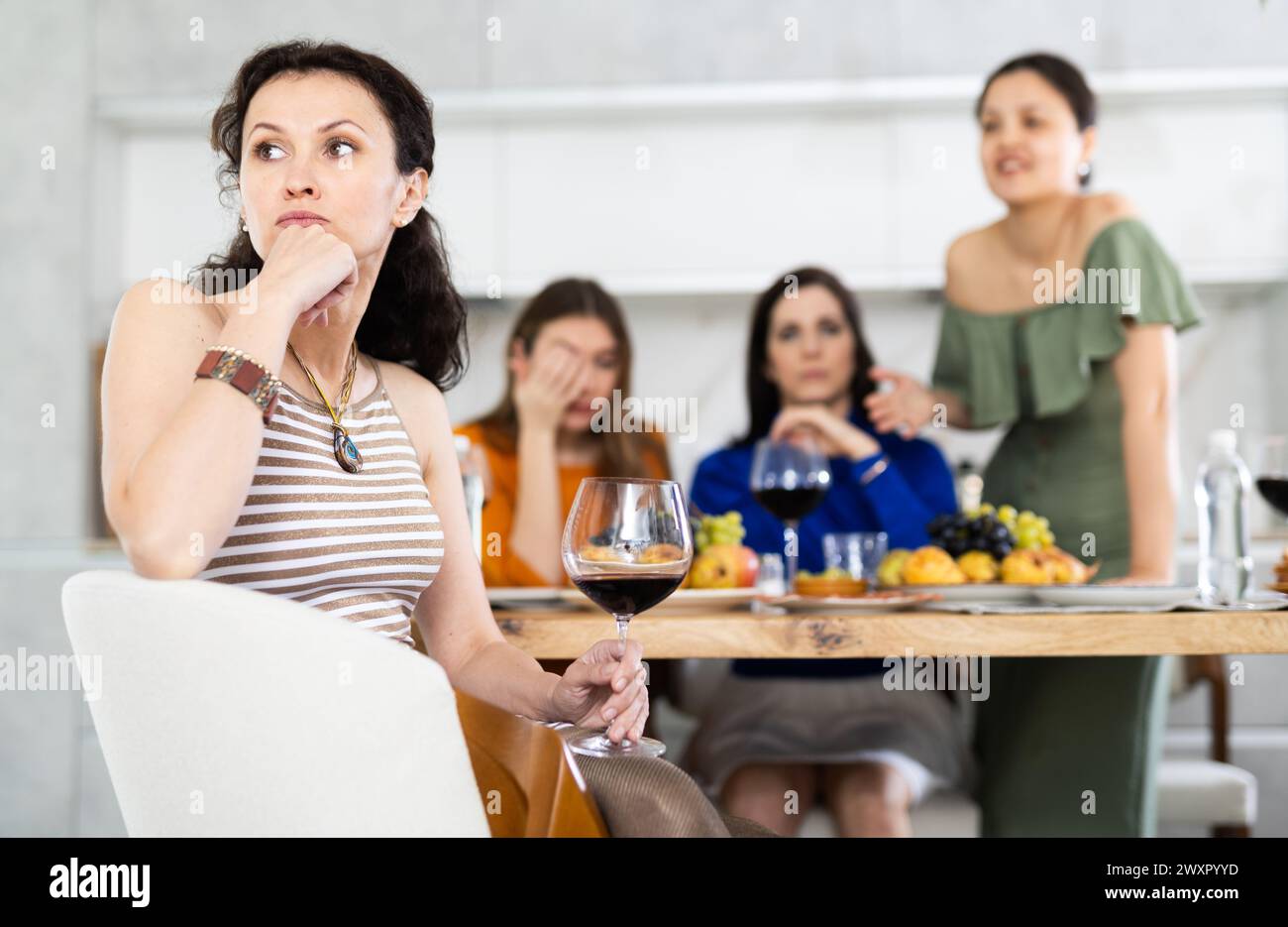 Miffed woman during disagreement with friends at house party Stock Photo