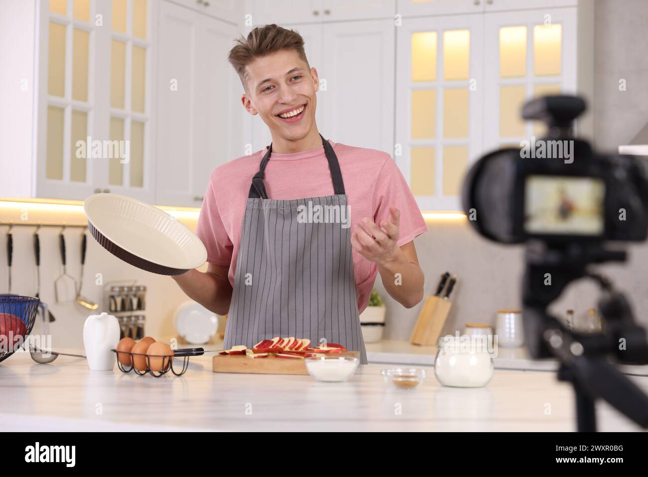Smiling food blogger explaining something while recording video in kitchen Stock Photo