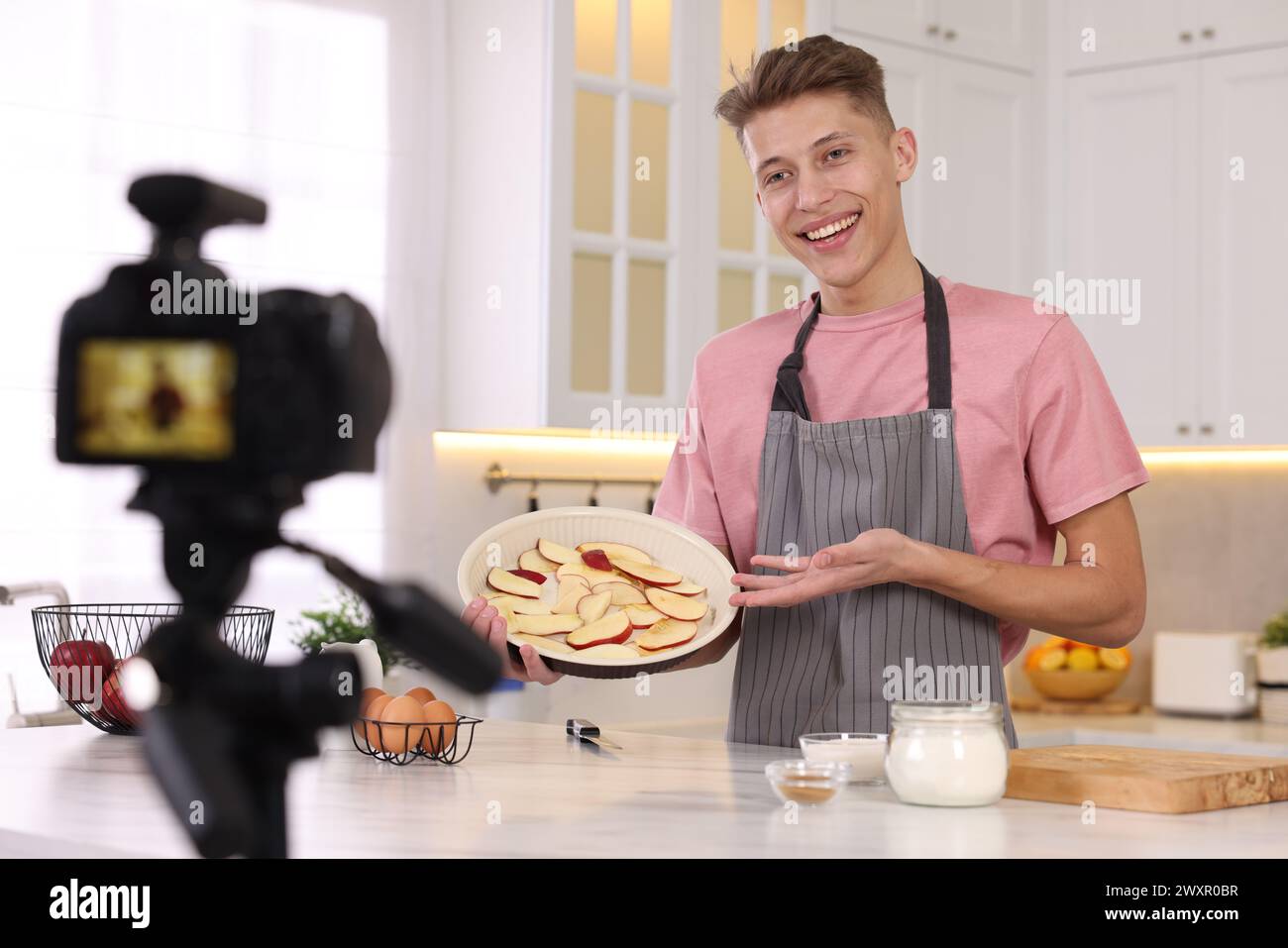 Smiling food blogger explaining something while recording video in kitchen Stock Photo