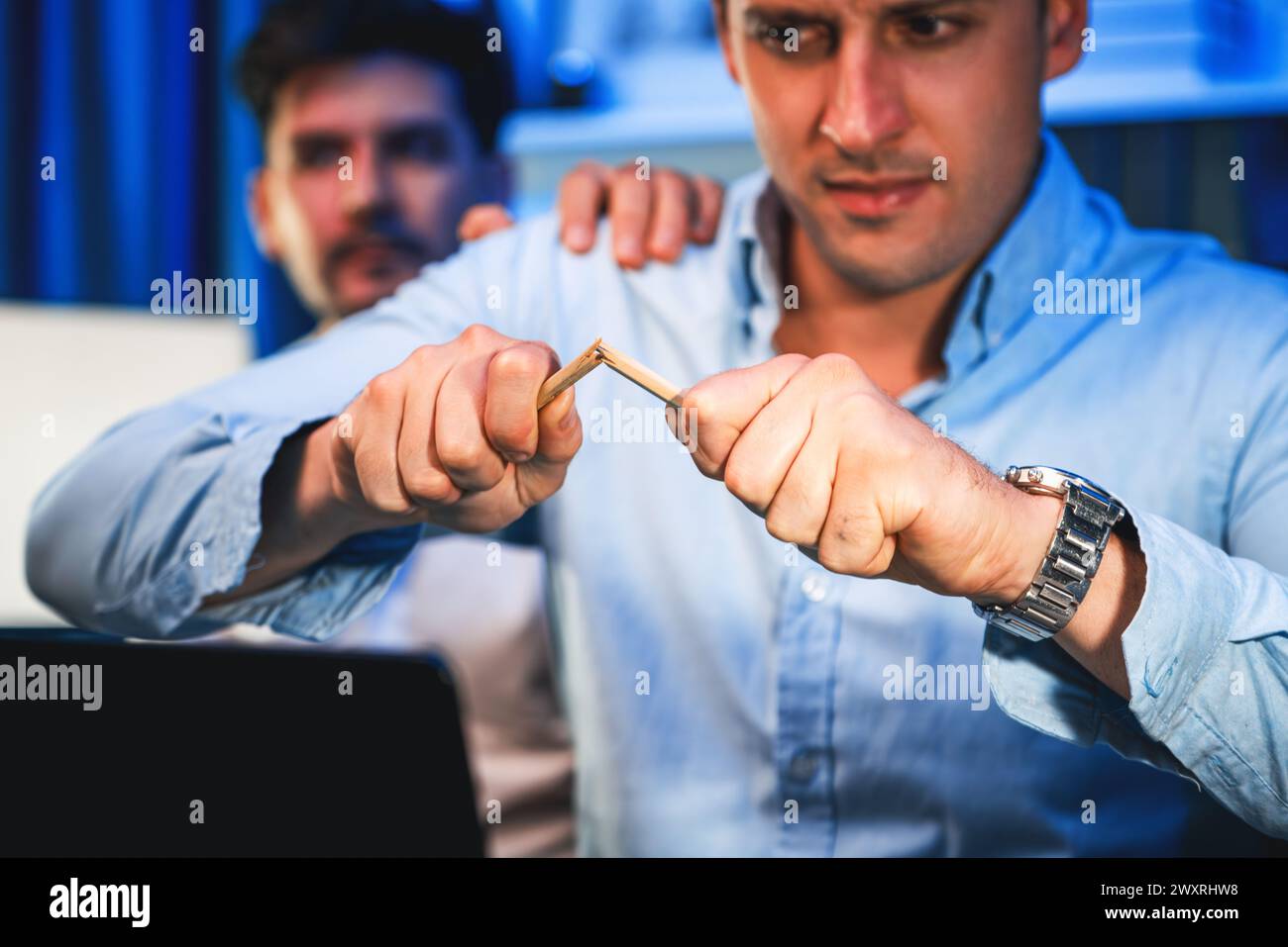 Stressful burnout of businessman destroying pencil for venting emotion in overwork load at night time, supported by business partner to solve issue Stock Photo