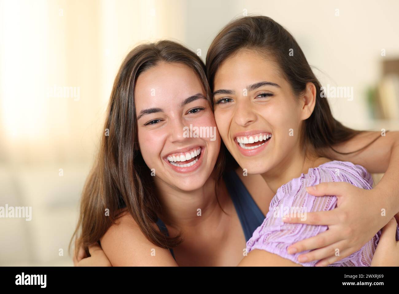 Front view portrait of two happy women with perfect smiles at home Stock Photo