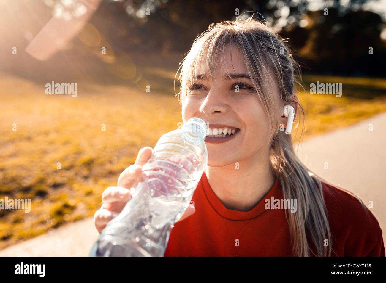Young woman in park drinking water after running Stock Photo Alamy