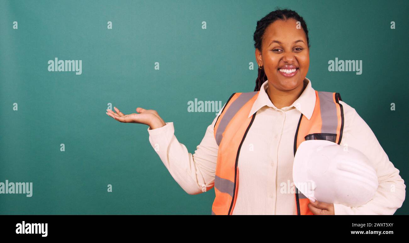 Young Black construction worker gestures smiling, working on site Stock Photo