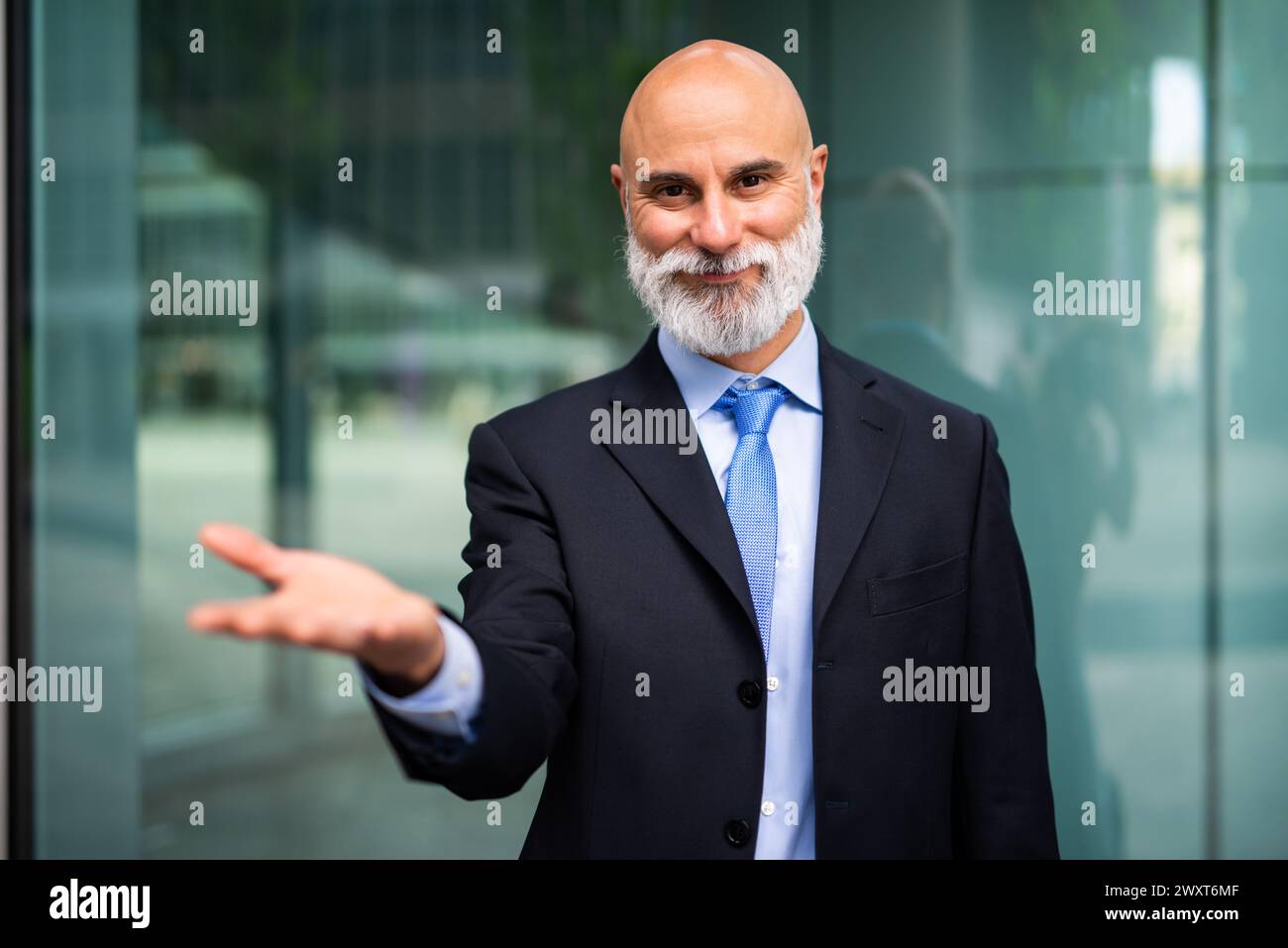 Mature bald stylish business man portrait with a white beard outdoor showing an open hand Stock Photo