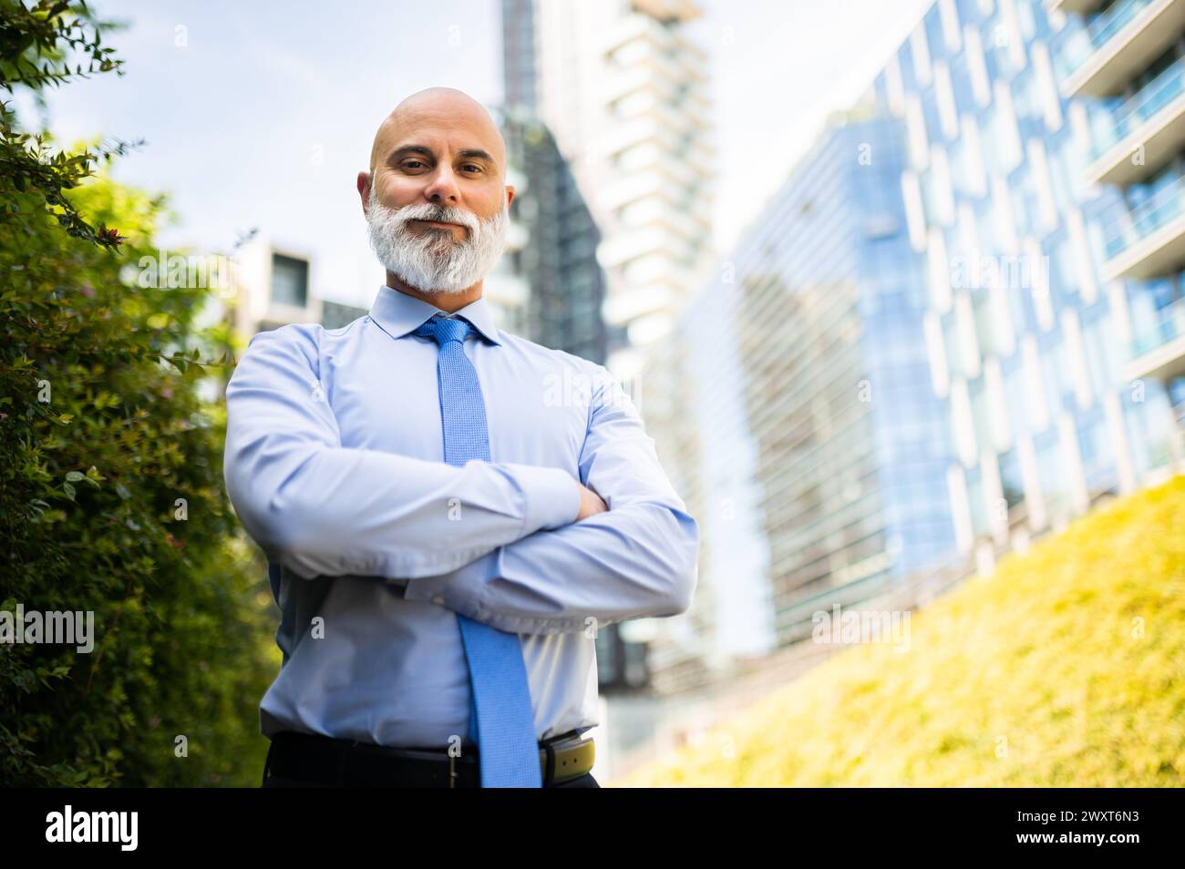 Mature bald stylish business man portrait with a white beard outdoor with folded arms Stock Photo