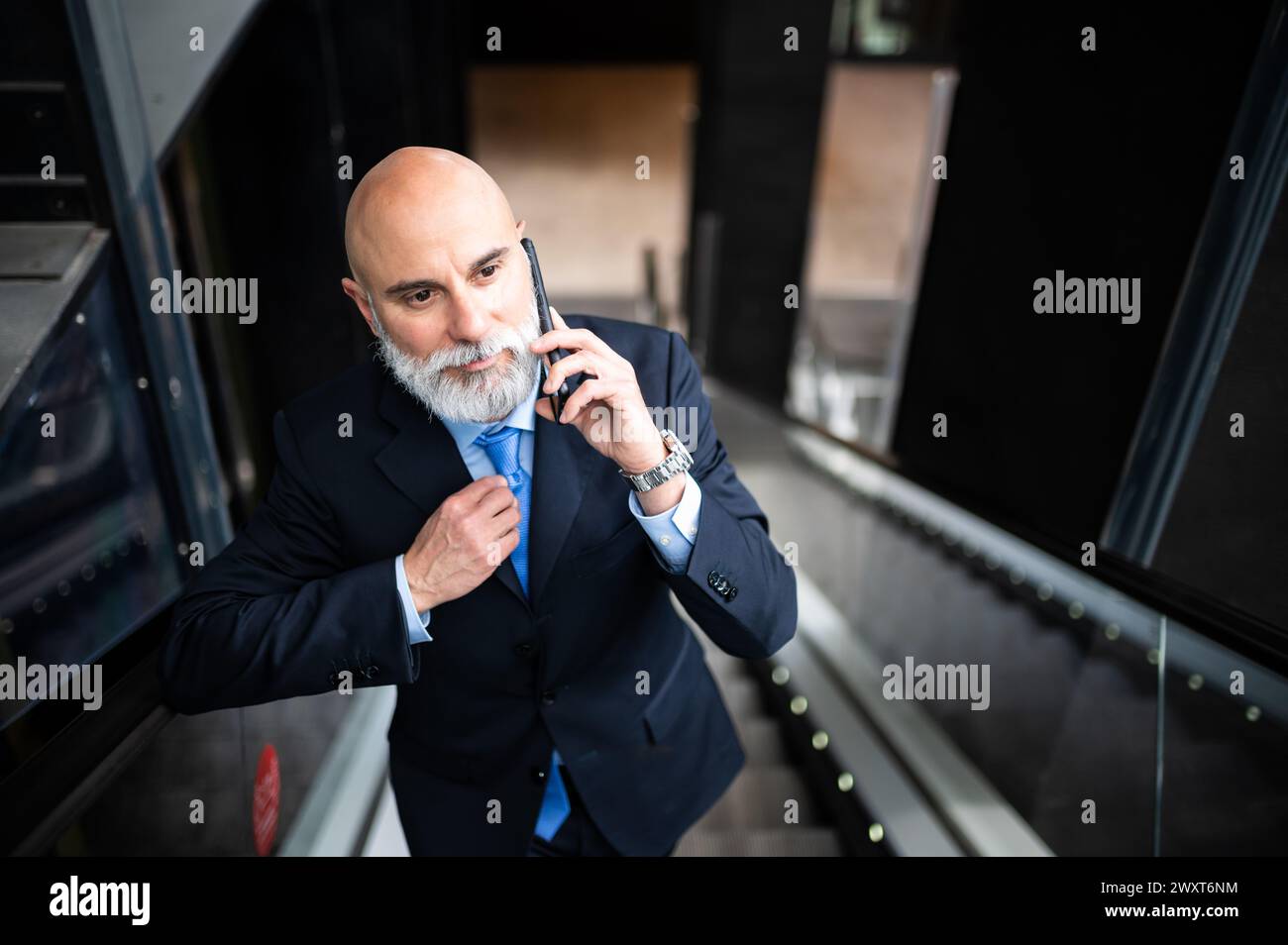 Stylish senior manager on the phone on mobile stairs Stock Photo