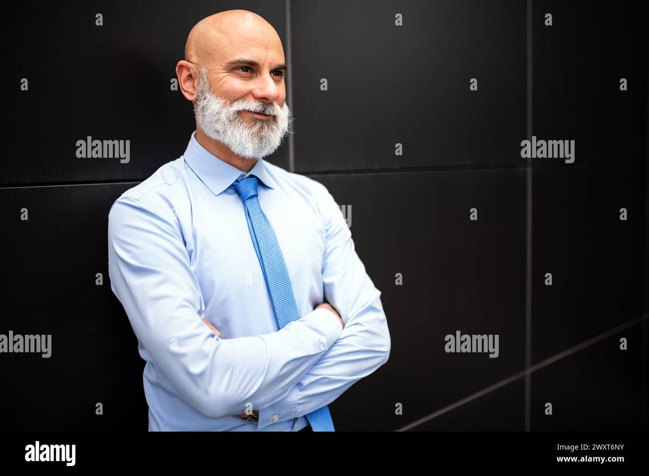 Mature bald stylish business man portrait with a white beard outdoor with folded arms Stock Photo