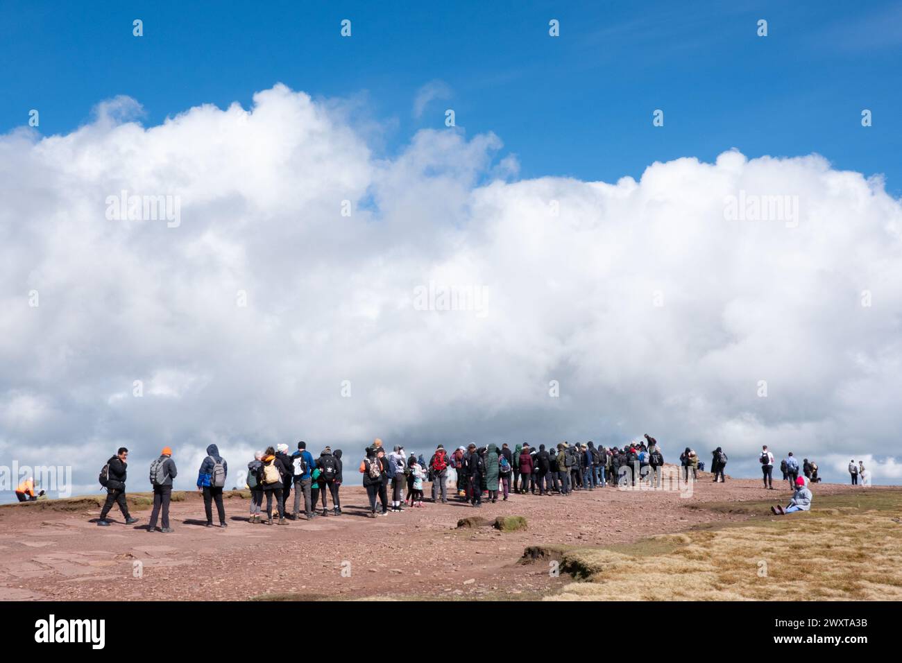 Brecon Beacons, Wales. A line hill walkers and climbers queue to take a picture by the trig point at the top of Pen Y Fan. The Brecons highest point Stock Photo