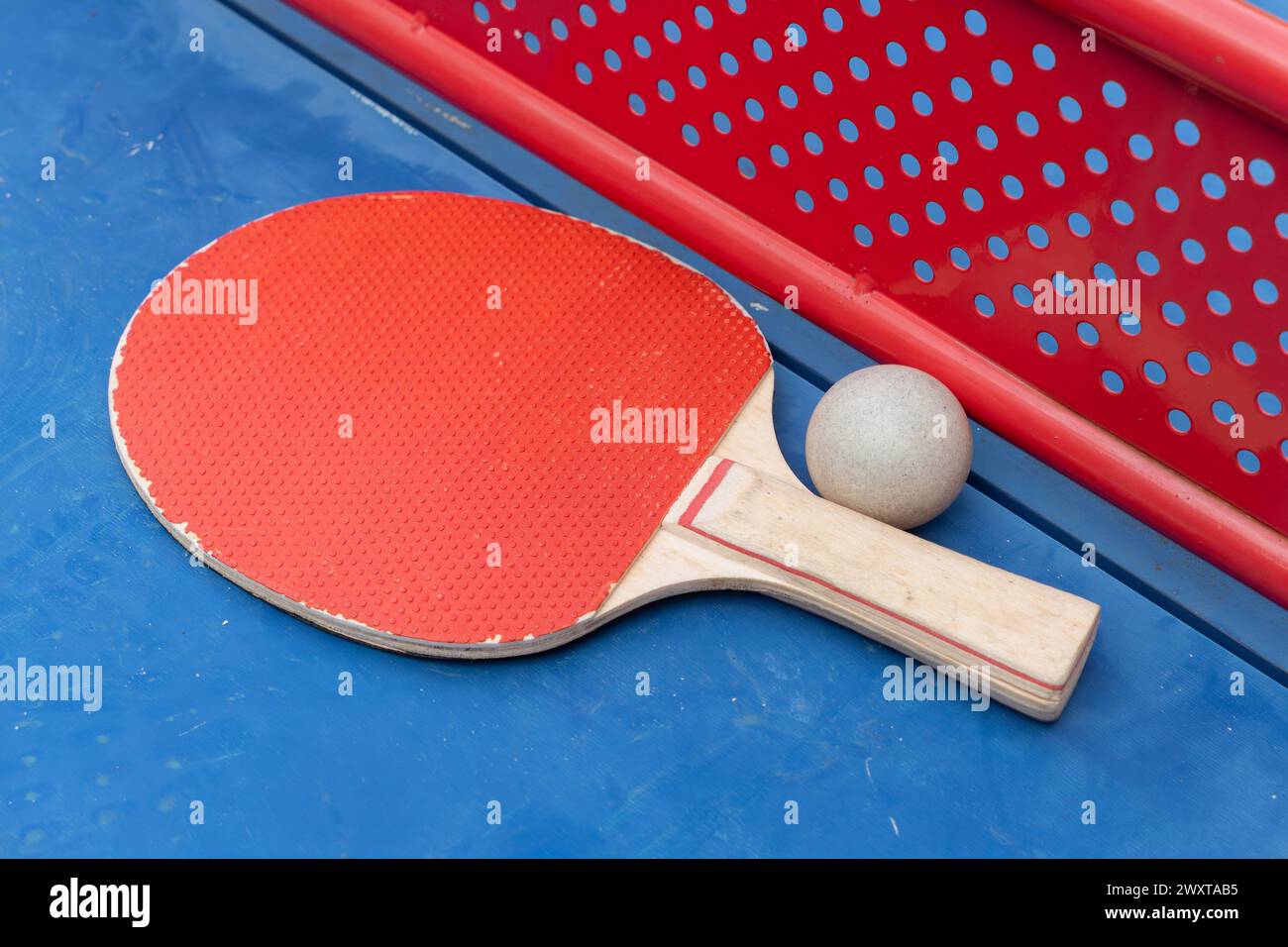 pingpong racket and ball and net on a blue pingpong table at horizontal composition Stock Photo