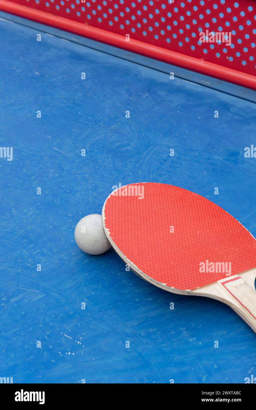 pingpong racket and ball and net on a blue pingpong table at vertical composition Stock Photo