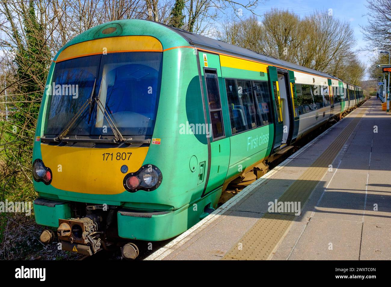 A Southern Railway train in green and yellow livery stands with its doors open at an empty station platform Stock Photo