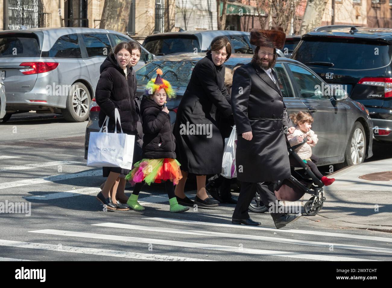 A Purim holiday street scene where it's customary for people to wear costumes and for some men to wear shtreimel fur hats. In Brooklyn, New York. Stock Photo