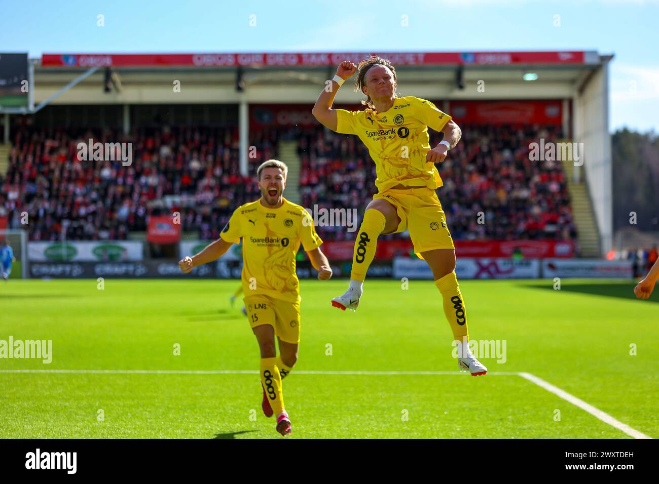 Fredrikstad, Norway, 1st April 2024.  Bodø/Glimt's Fredrik Bjørkan chases Bodø/Glimt's August Mikkelsen who celebrates scoring on his Bodø/Glimt debut in the Eliteserien match between Fredrikstad and Bodø/Glimt at Fredrikstad stadium.  Credit: Frode Arnesen/Alamy Live News Stock Photo