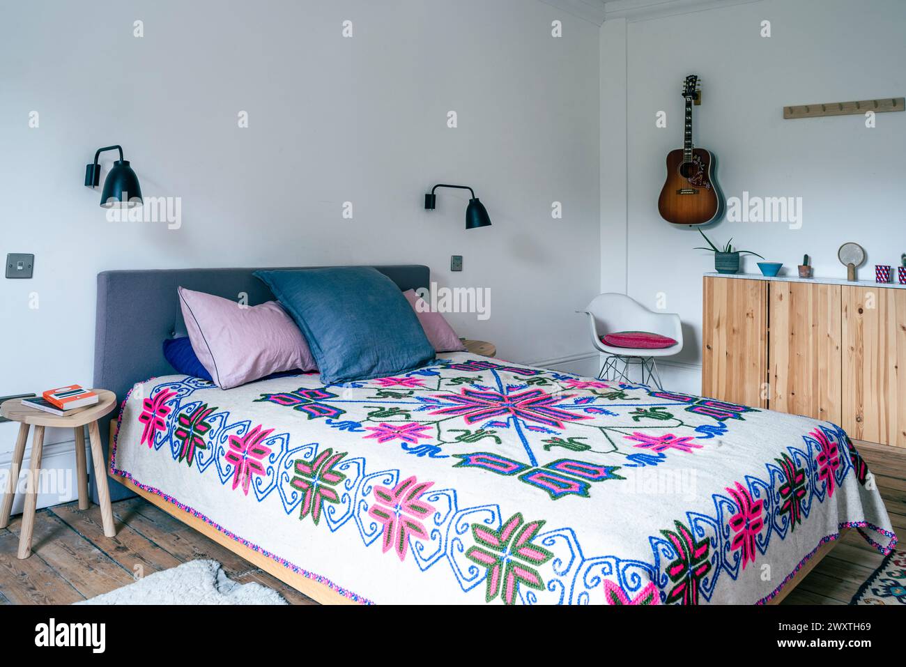Embroidered bedspread with guitar in East London home, UK Stock Photo