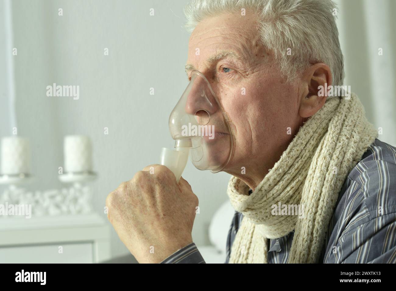 An elderly man is sick and uses an inhaler Stock Photo