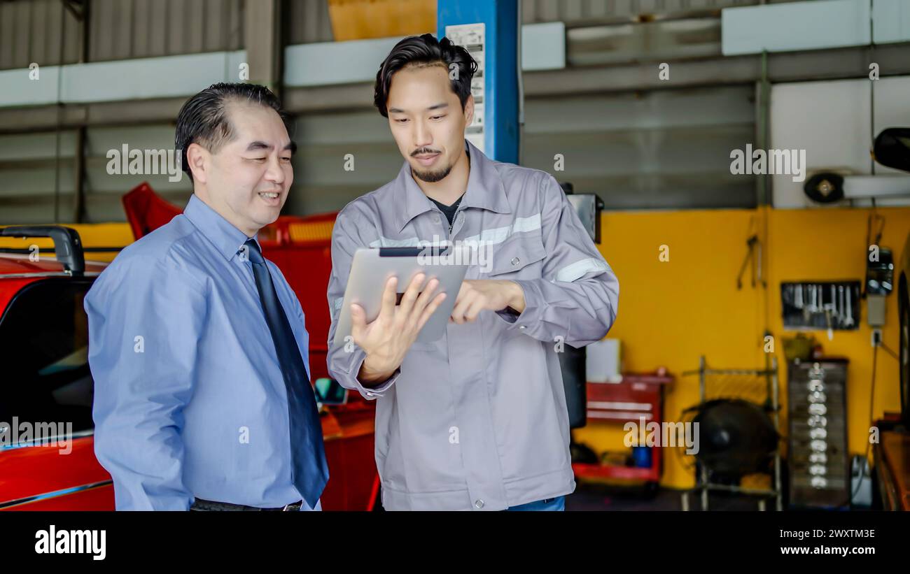 Two auto technicians using a digital tablet while repairing a car Stock Photo