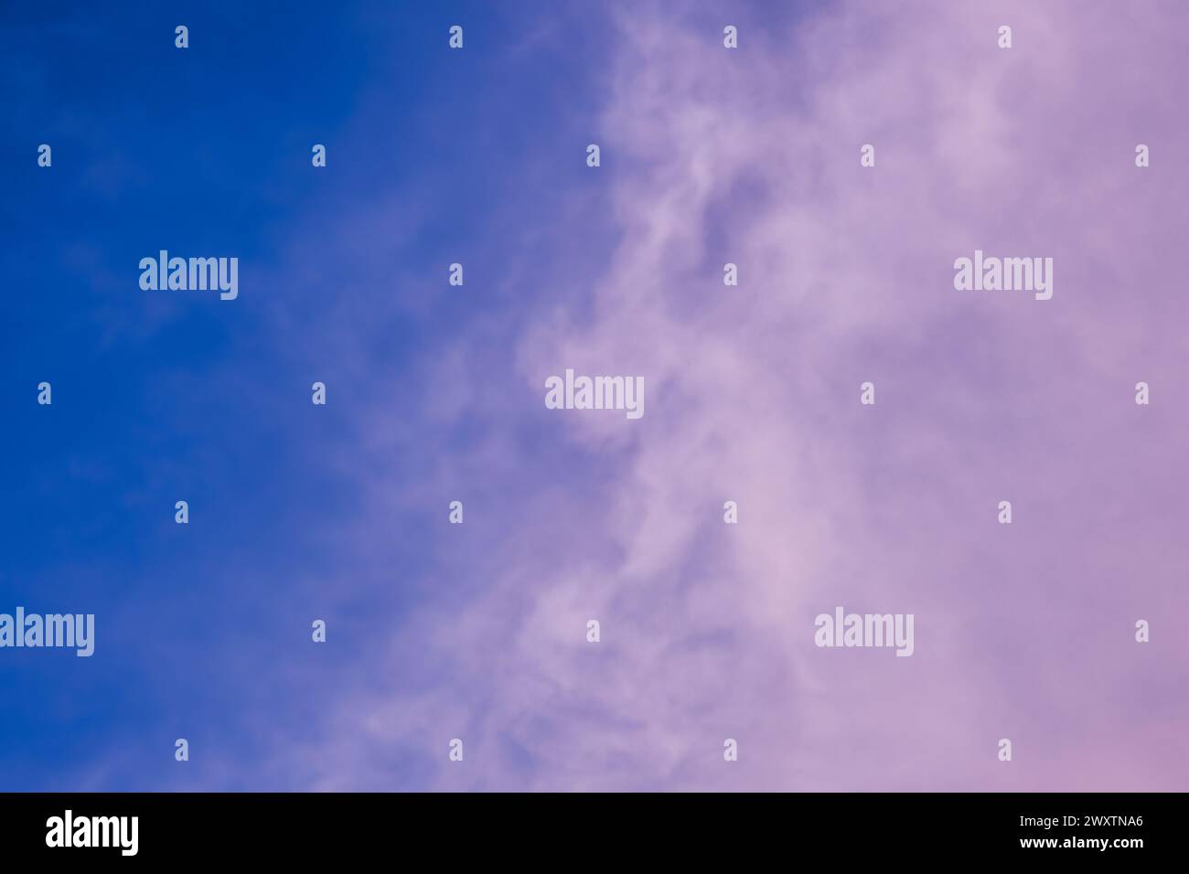 The sky at dusk was a breathtaking sight, with electric blue hues blending into shades of purple clouds. A few cumulus clouds hovered above the horizon, creating a stunning meteorological phenomenon Stock Photo