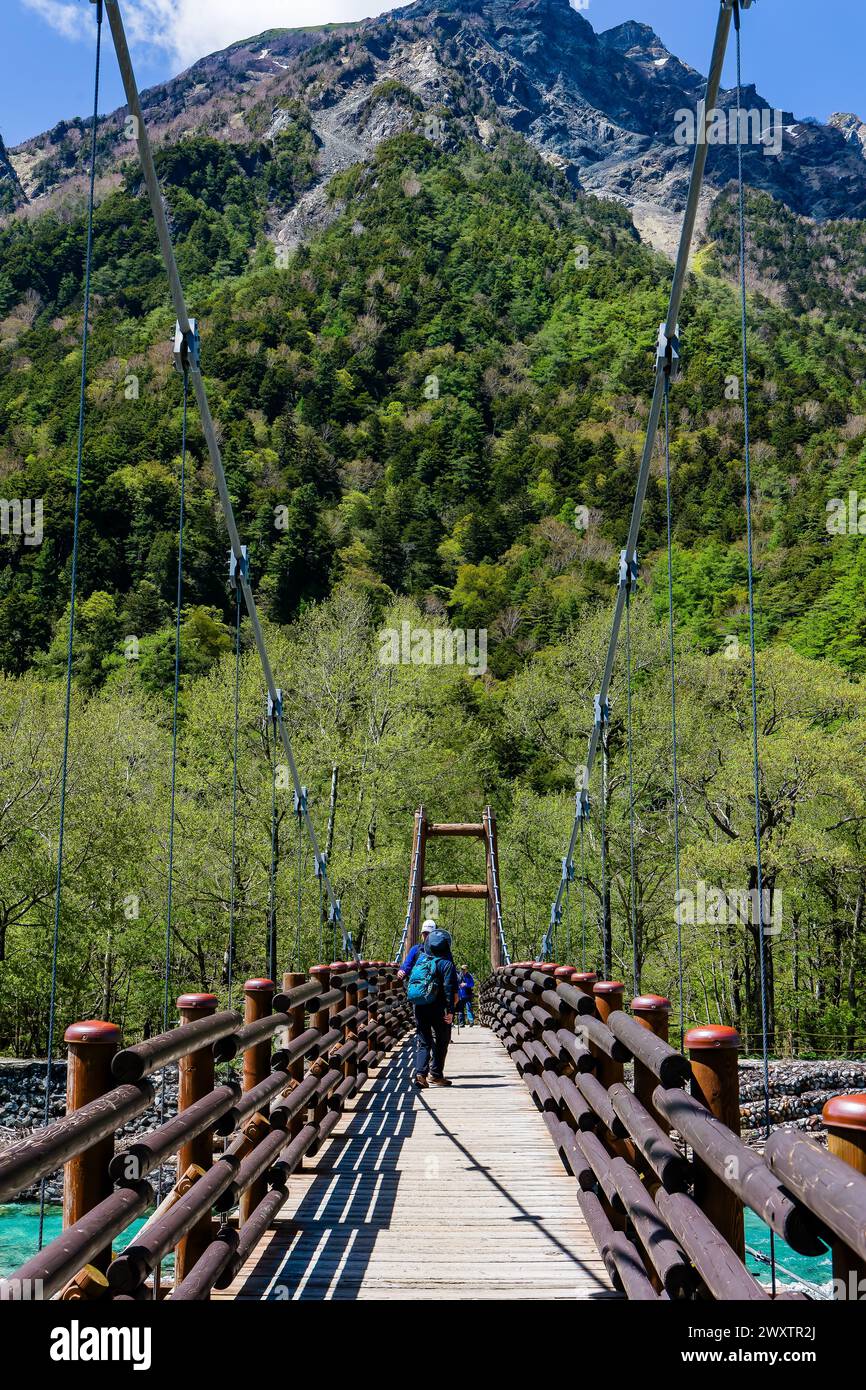 KAMIKOCHI, JAPAN - MAY 24 2023: Hikers crossing the Myojin suspension bridge over the Azusa River in Kamikochi, Nagano, Japan Stock Photo