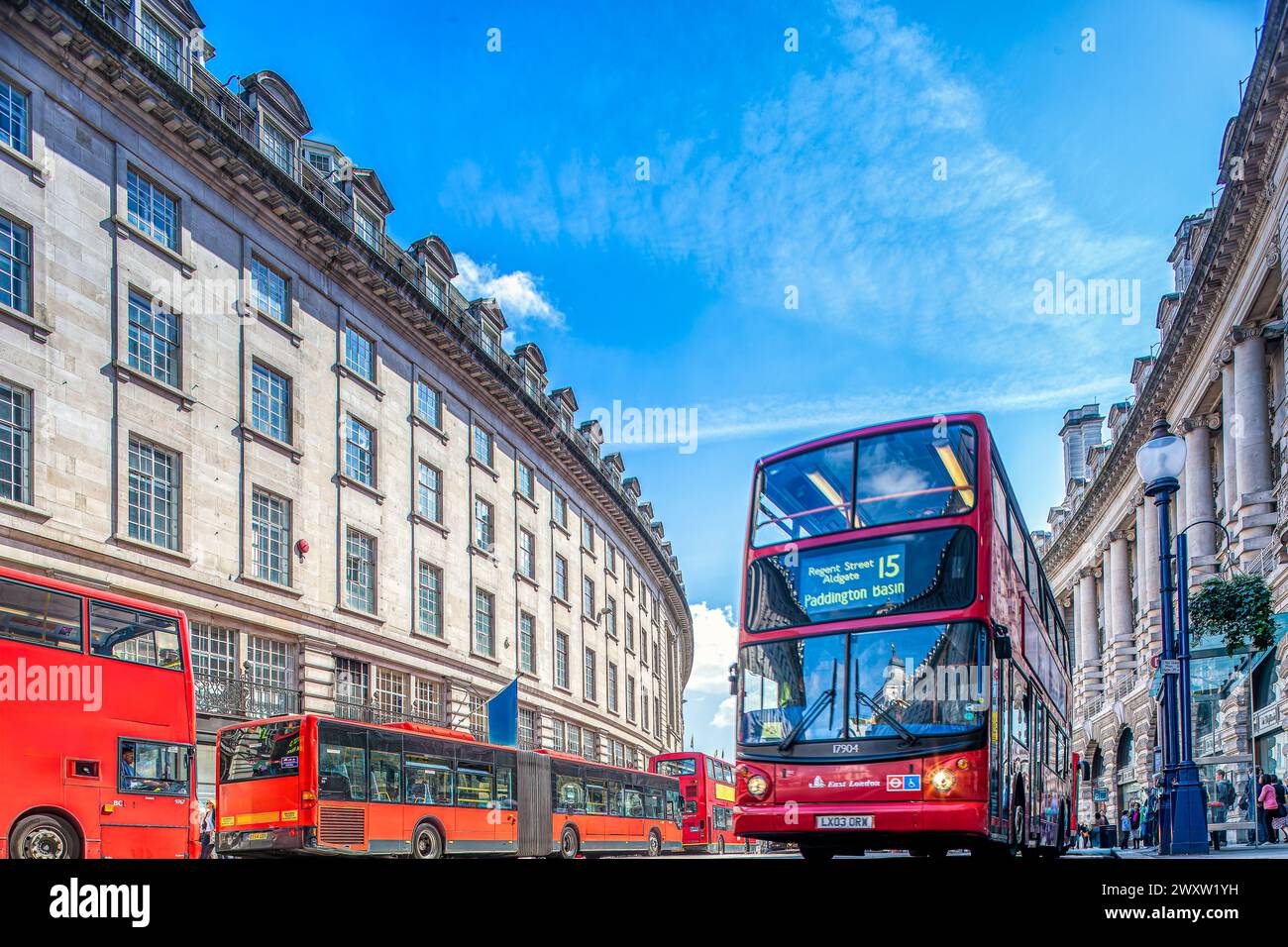 Double-decker buses travel down the bustling Regent Street under a clear blue sky. Stock Photo