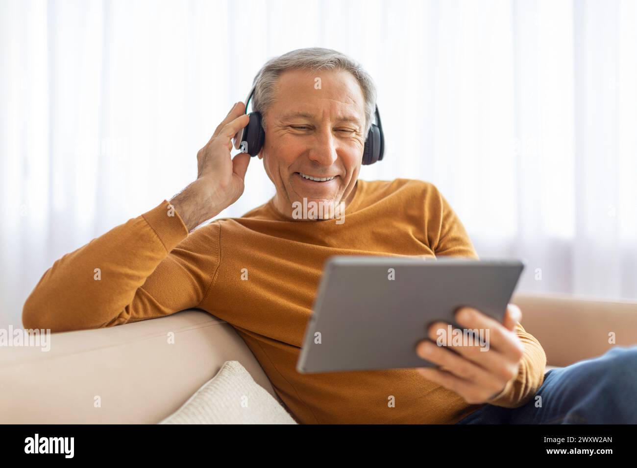 Elderly man with headphones using a tablet Stock Photo