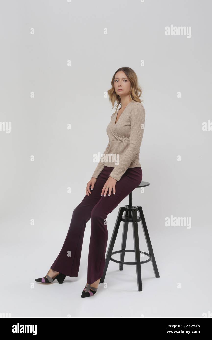 Serie of studio photos of young female model wearing basic flared purple trousers and knitted beige shirt, fall winter fashion collection Stock Photo
