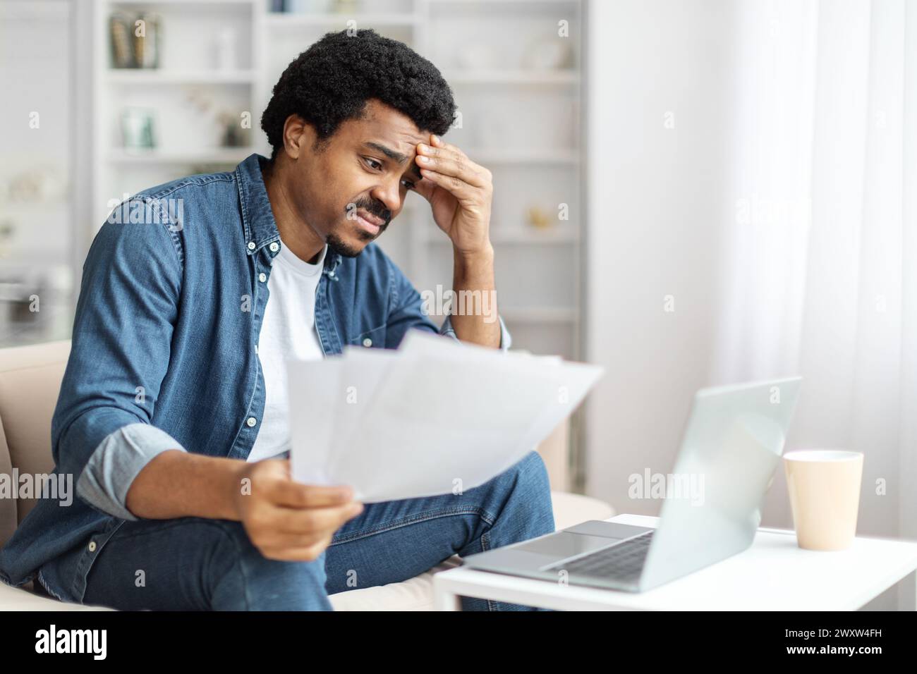 Concerned Black Man Reviewing Documents at Home Stock Photo