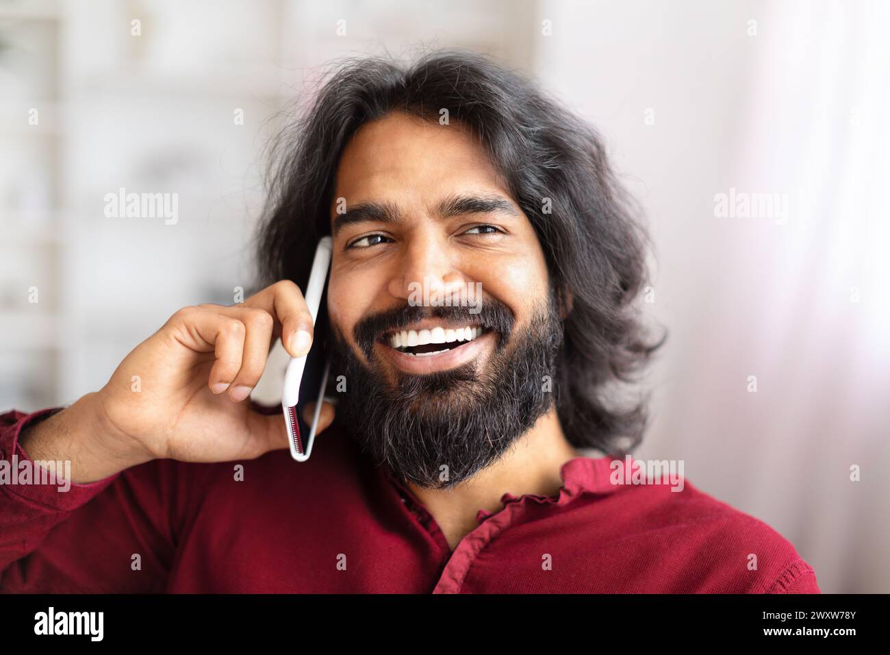 Man smiling while talking on phone at home Stock Photo