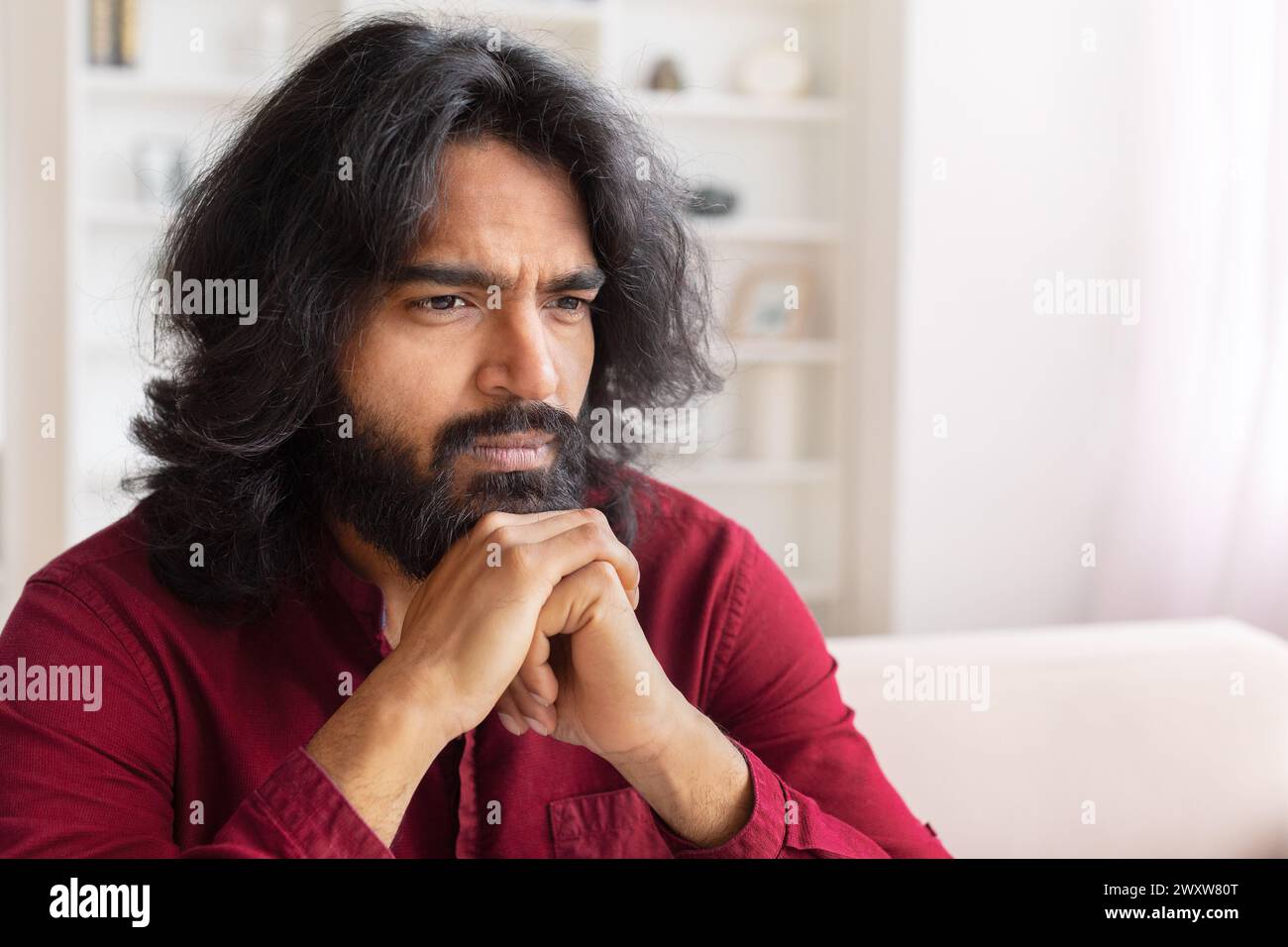 Man pondering in a well-lit room at home Stock Photo