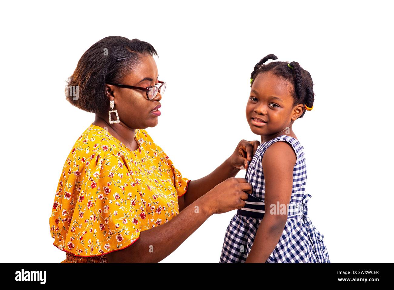 a charming businesswoman in glasses on her knees on white background adjusting the button of her schoolgirl daughter. Stock Photo