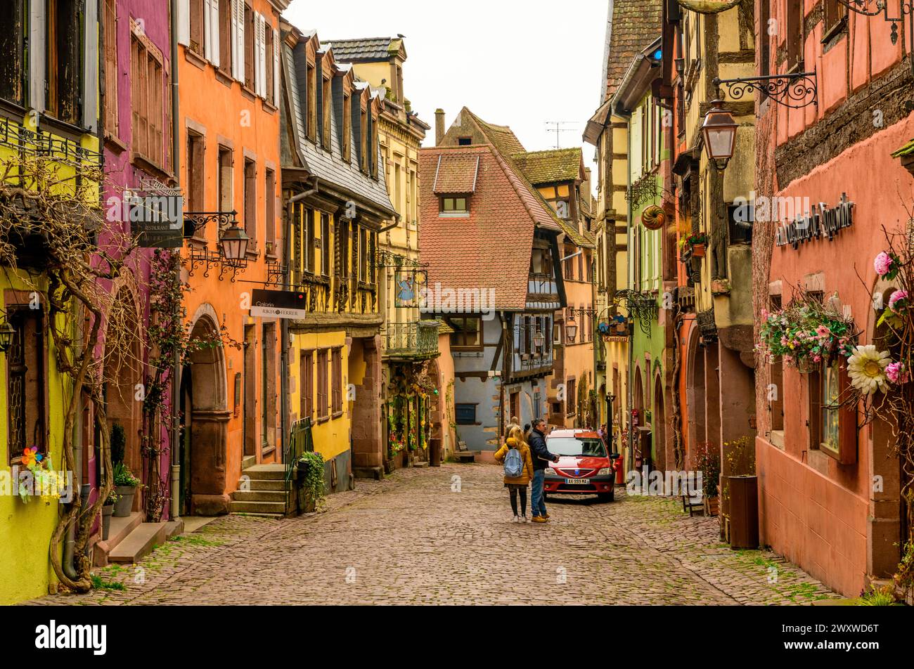RIQUEWIHR, FRANCE - MARCH 30, 2024: People walking between half-timbered houses Stock Photo