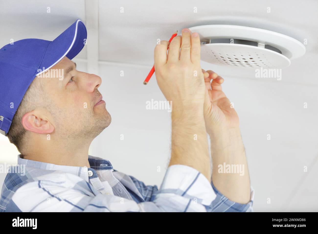 technician reaching up to open filter holder in ceiling Stock Photo