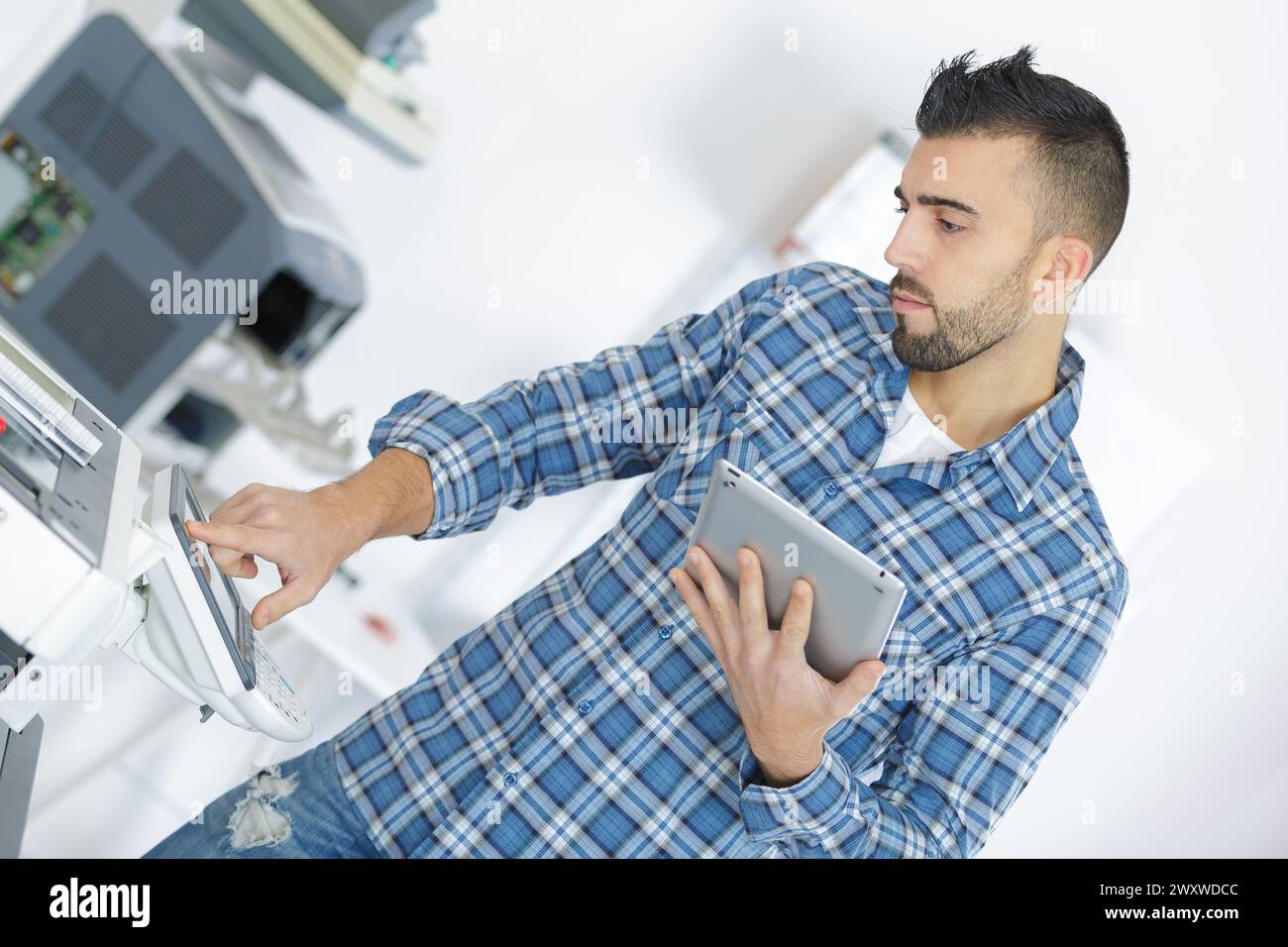 technician using a tablet to fix a printer Stock Photo