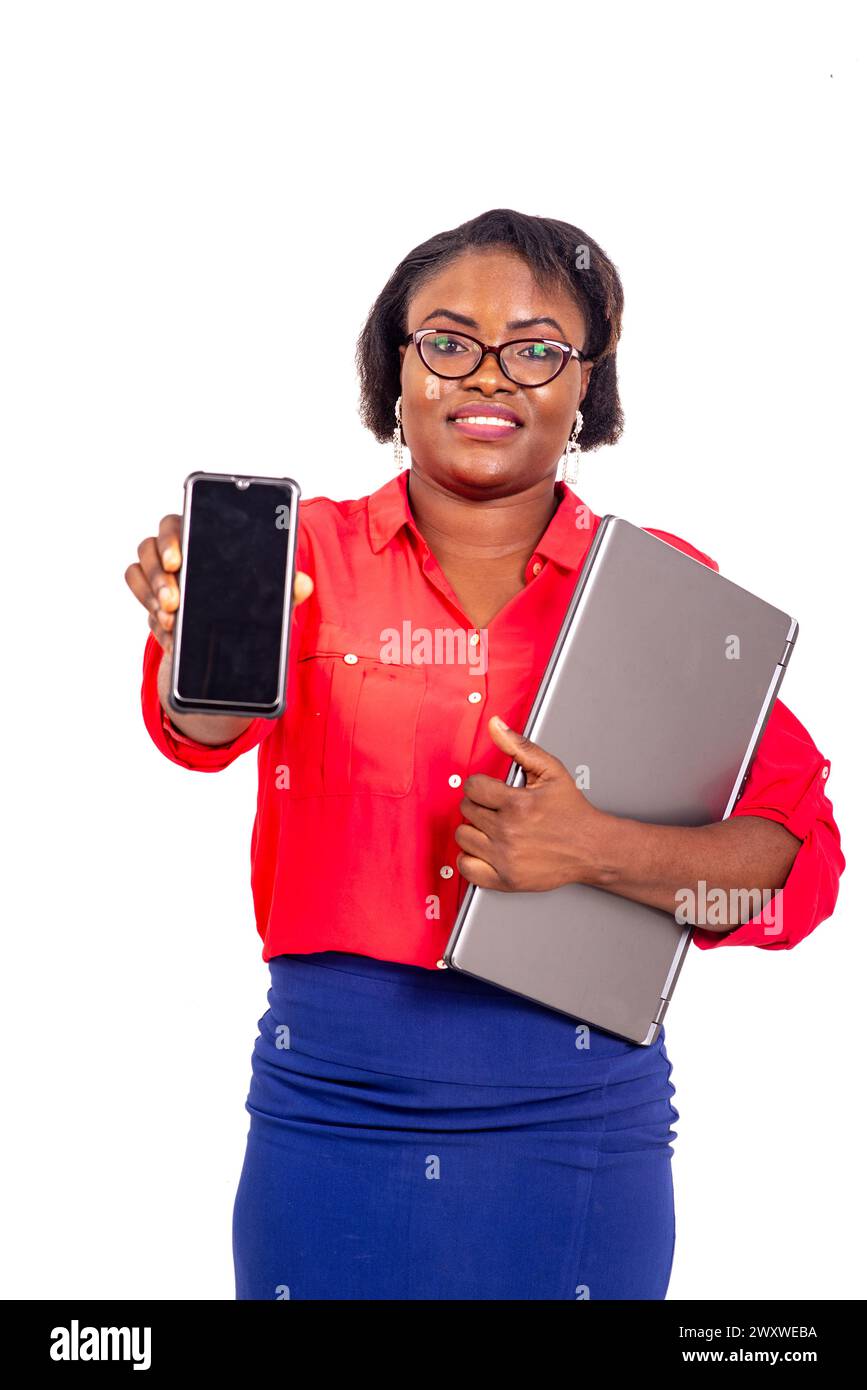 portrait of a beautiful adult business woman holding laptop and showing mobile phone while smiling. Stock Photo