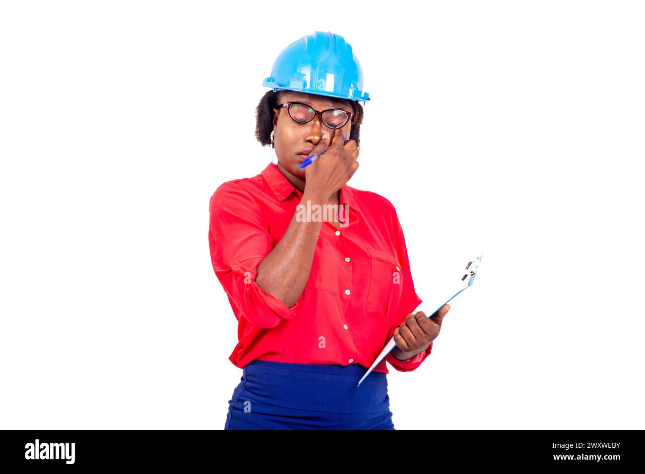 beautiful female engineer wearing blue safety helmet, holding clipboard and cleaning her eyes with finger. Stock Photo